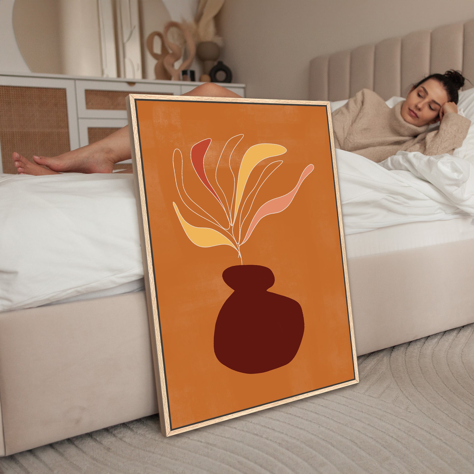 a woman laying on a bed next to a picture of a vase